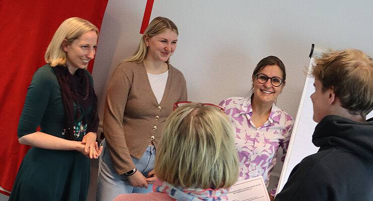 Fünf Personen stehen im Kreis zusammen.