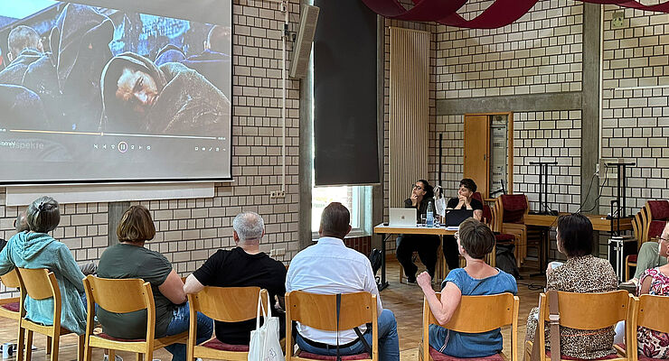 Menschen, die auf eine Leinwand schauen, sind von hinten zu sehen.